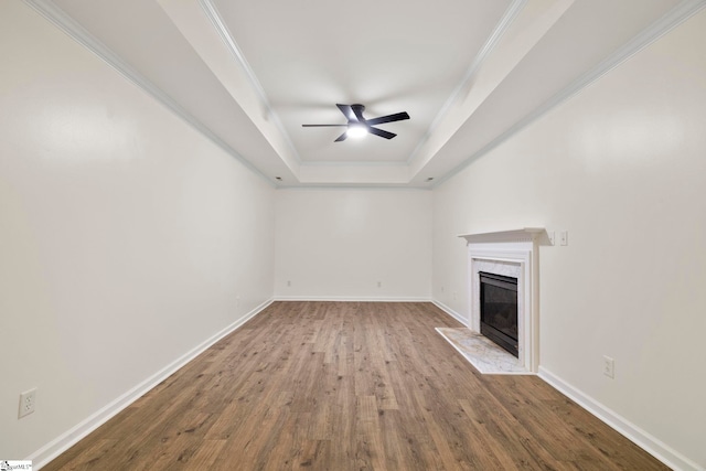 unfurnished living room with a premium fireplace, ceiling fan, ornamental molding, and hardwood / wood-style flooring