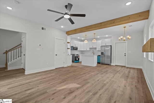 unfurnished living room featuring ceiling fan with notable chandelier, beamed ceiling, light hardwood / wood-style flooring, and sink