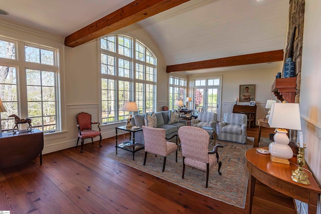 living room with vaulted ceiling with beams, a large fireplace, and wood-type flooring