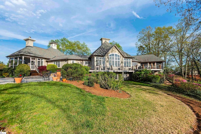 rear view of house featuring a sunroom and a lawn