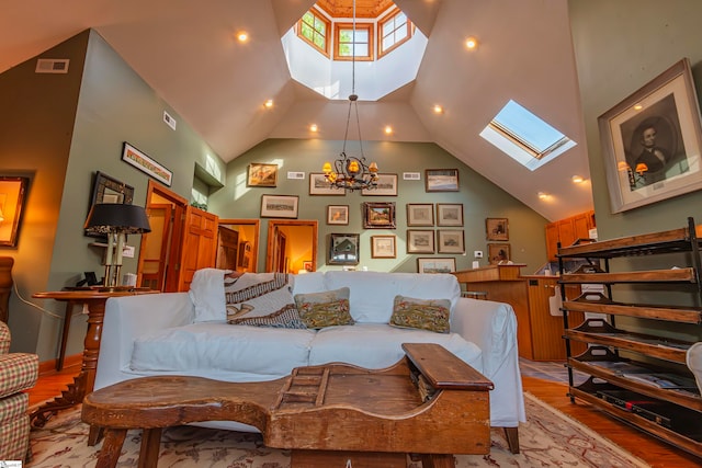 living room with a high ceiling, a skylight, an inviting chandelier, and light hardwood / wood-style floors