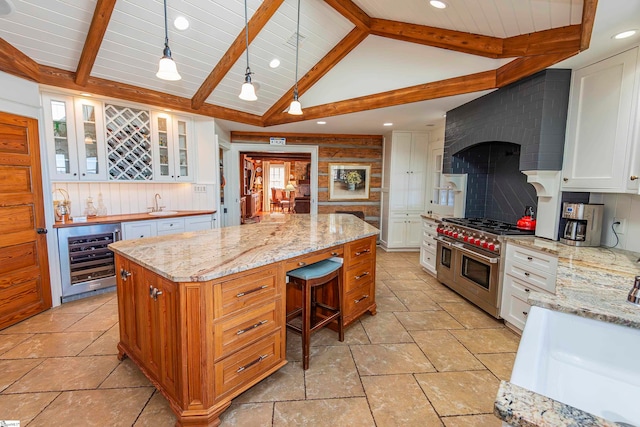 kitchen with double oven range, white cabinets, wine cooler, decorative light fixtures, and a kitchen island