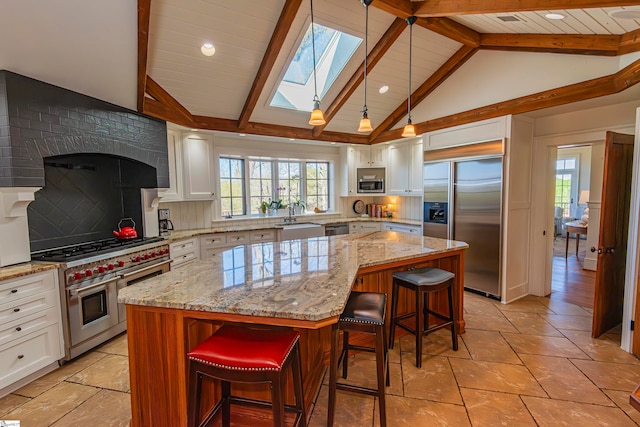 kitchen with a center island, built in appliances, lofted ceiling with skylight, and a breakfast bar area