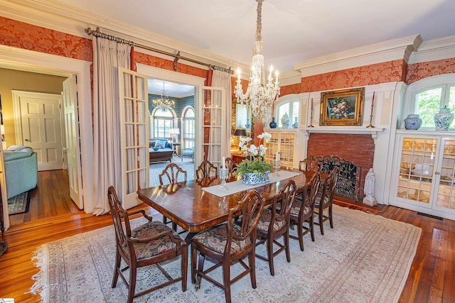 571 E Main St, Spartanburg, SC 29302 - dining space featuring a chandelier, hardwood / wood-style flooring, ornamental molding, a brick fireplace, and wallpapered walls