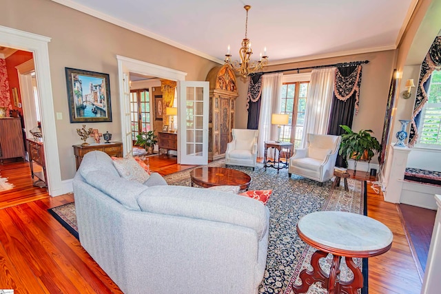 living room with an inviting chandelier, hardwood / wood-style floors, crown molding, and plenty of natural light