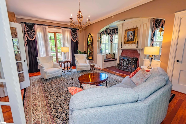 living room featuring hardwood / wood-style floors, a fireplace, an inviting chandelier, and crown molding