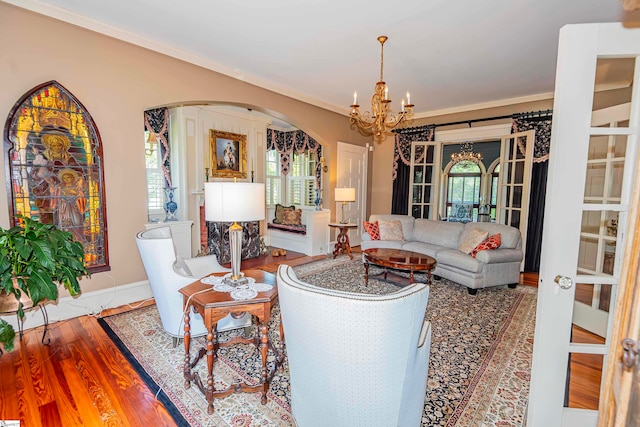 living room featuring french doors, wood-type flooring, an inviting chandelier, and crown molding