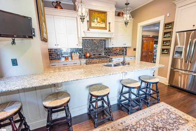 kitchen with light stone counters, stainless steel appliances, sink, a breakfast bar, and dark wood-type flooring