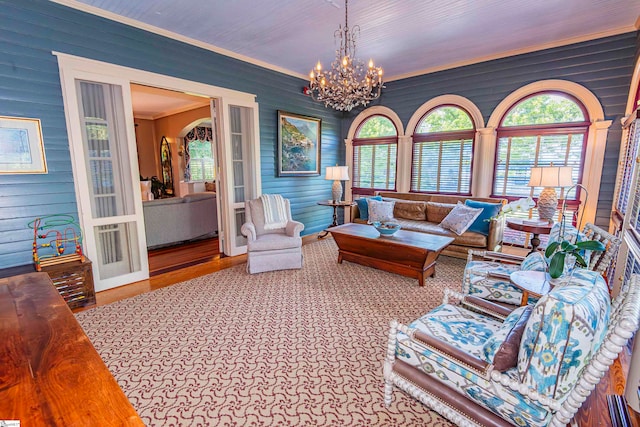 living room with light hardwood / wood-style flooring, a notable chandelier, wooden walls, and crown molding