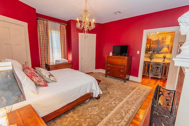 bedroom with wood-type flooring and a notable chandelier