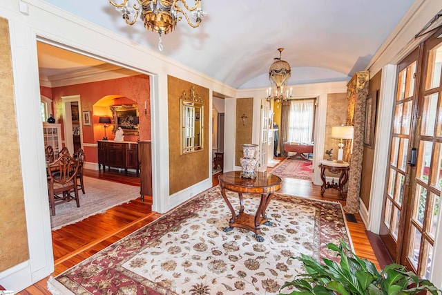 living area with hardwood / wood-style floors, a notable chandelier, crown molding, and vaulted ceiling