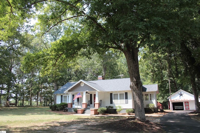 ranch-style house with covered porch, an outdoor structure, and a garage