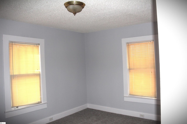 unfurnished room featuring dark colored carpet and a textured ceiling