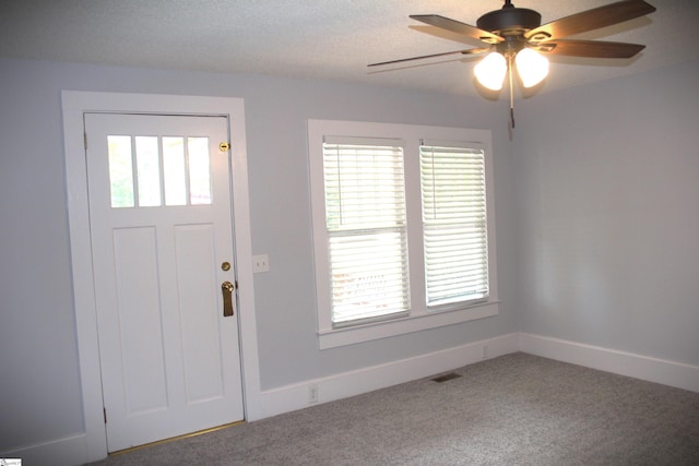 carpeted entrance foyer with a textured ceiling, plenty of natural light, and ceiling fan