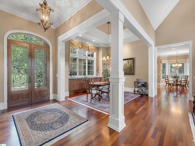 entryway featuring crown molding, decorative columns, dark hardwood / wood-style flooring, an inviting chandelier, and french doors