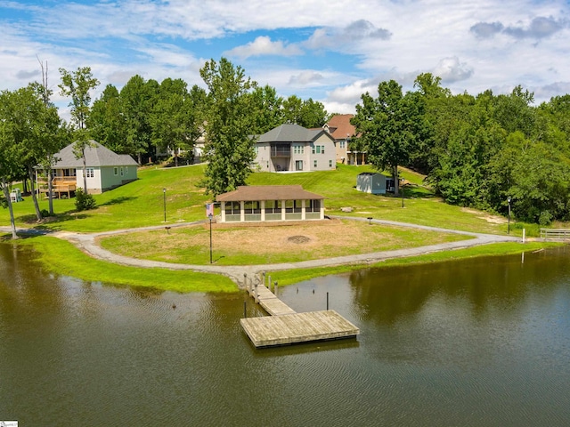 back of house with a sunroom, a lawn, and a water view