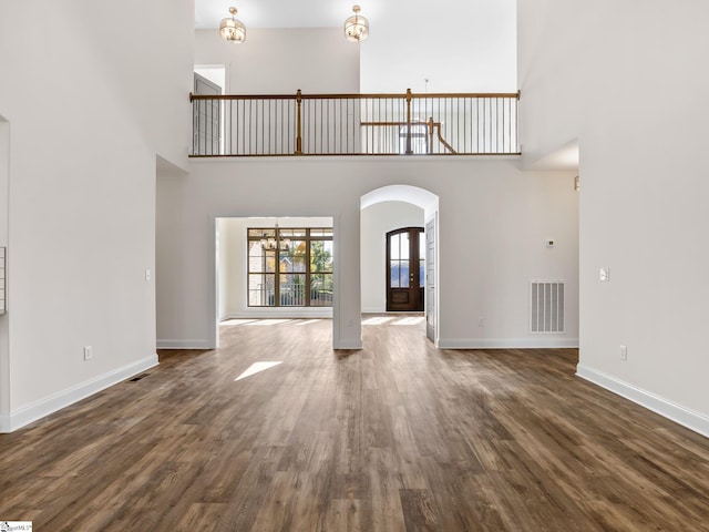 unfurnished living room with a towering ceiling and dark hardwood / wood-style flooring