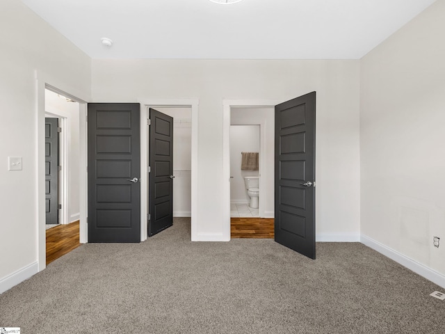 unfurnished bedroom featuring ensuite bathroom and carpet flooring