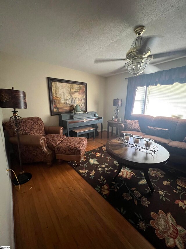 living room featuring a textured ceiling, ceiling fan, and hardwood / wood-style flooring