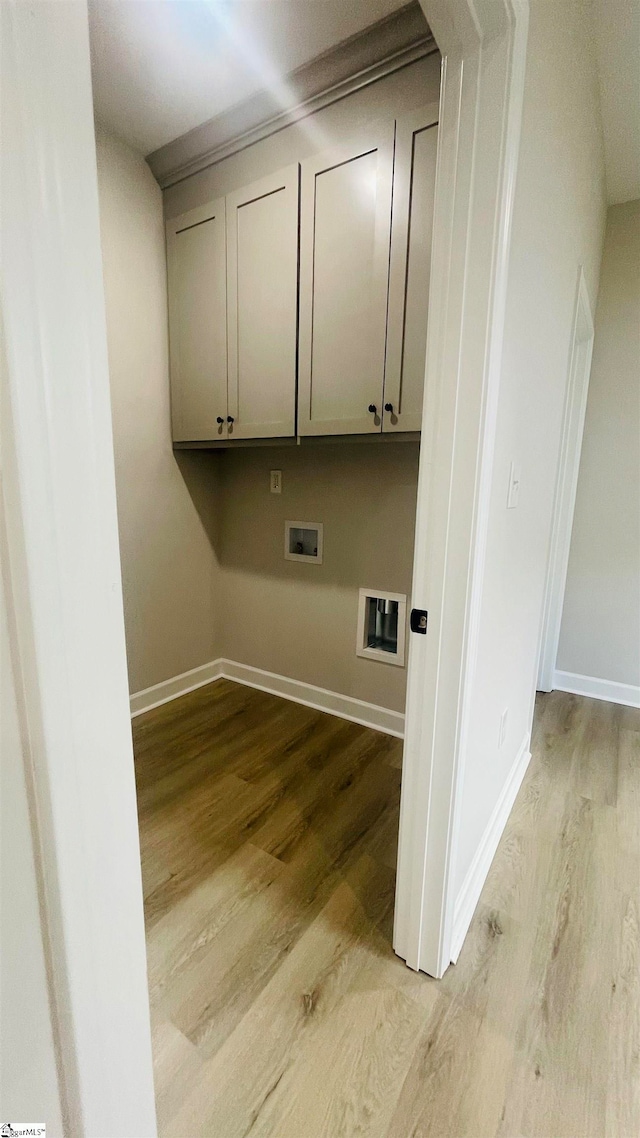 washroom featuring light wood-type flooring, washer hookup, and cabinets