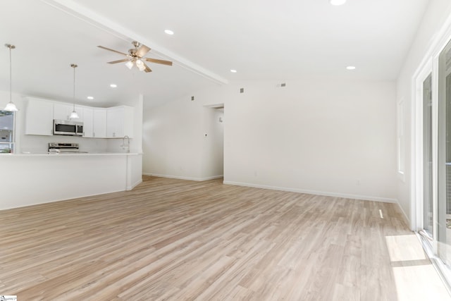 unfurnished living room featuring light wood-type flooring, baseboards, a ceiling fan, and vaulted ceiling with beams