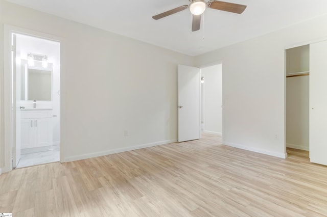 unfurnished bedroom featuring light wood-style flooring, ensuite bathroom, a closet, baseboards, and ceiling fan