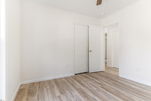 unfurnished bedroom featuring light wood finished floors, ceiling fan, baseboards, and a closet