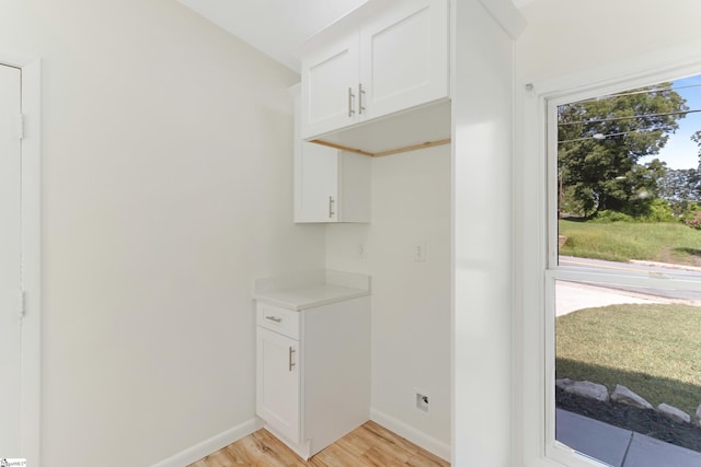 laundry area with light wood-type flooring and baseboards