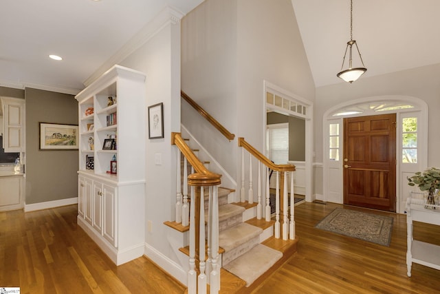 entrance foyer with lofted ceiling, ornamental molding, and light hardwood / wood-style floors