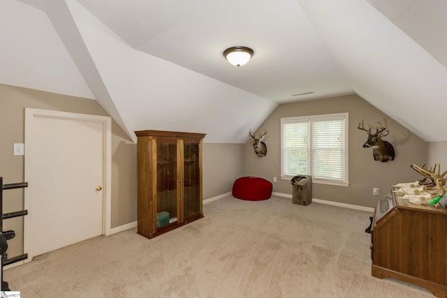 bonus room with lofted ceiling and light carpet