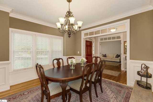 dining room with wood-type flooring, crown molding, and a notable chandelier