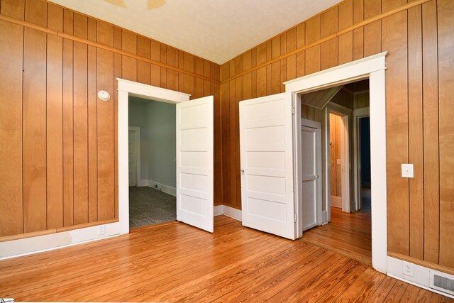 empty room featuring wooden walls and hardwood / wood-style flooring