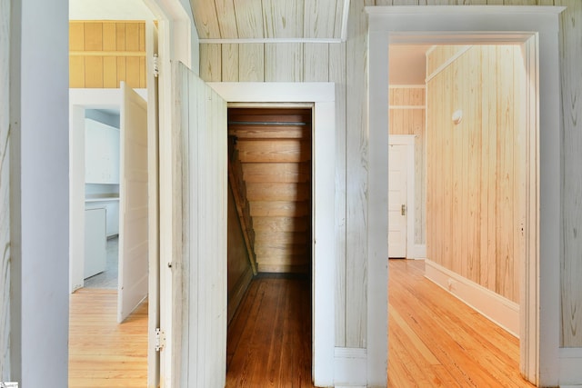 corridor with wood-type flooring and wooden walls