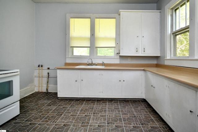 kitchen with a wealth of natural light, white range, sink, and white cabinets