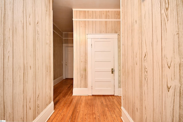 corridor with wood walls and hardwood / wood-style flooring