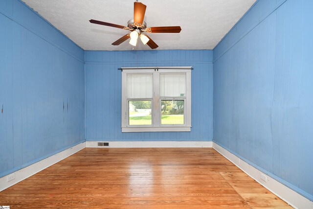 unfurnished room featuring a textured ceiling, light hardwood / wood-style flooring, and ceiling fan