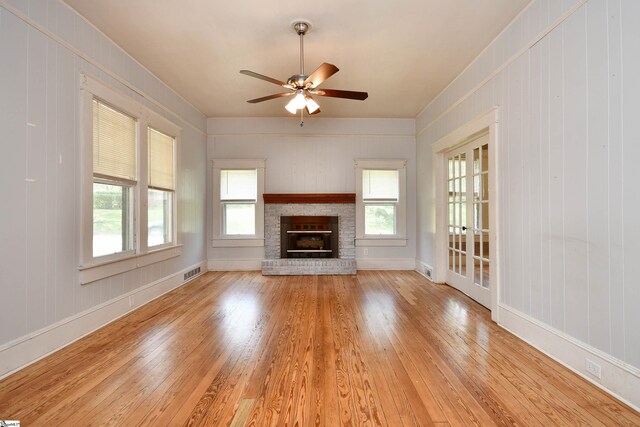 unfurnished living room featuring light wood-type flooring, ceiling fan, and a brick fireplace