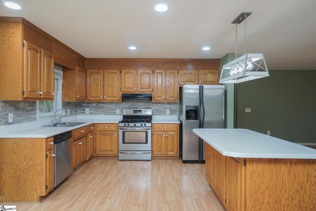 kitchen featuring light hardwood / wood-style flooring, decorative light fixtures, stainless steel appliances, sink, and extractor fan