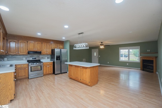 kitchen featuring light hardwood / wood-style flooring, a center island, ceiling fan, hanging light fixtures, and appliances with stainless steel finishes