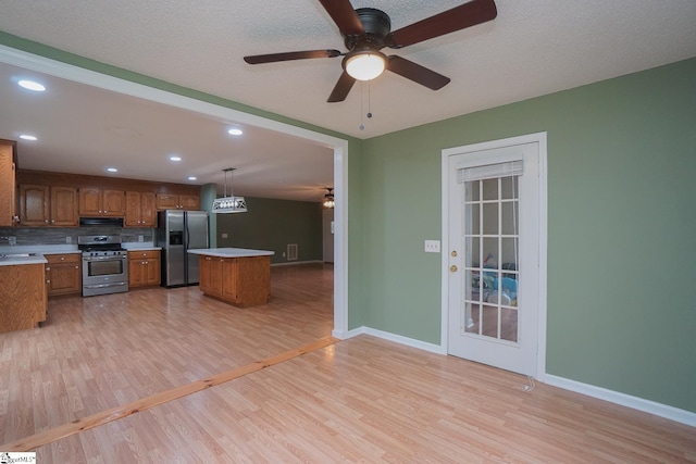 kitchen featuring light wood-type flooring, appliances with stainless steel finishes, pendant lighting, and ceiling fan