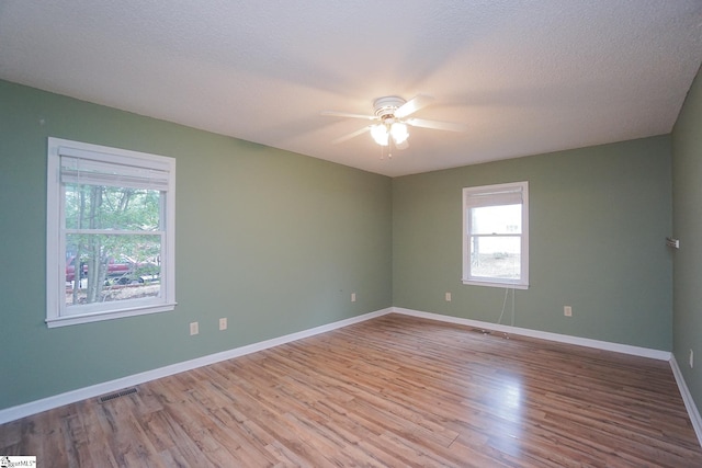 spare room with a textured ceiling, ceiling fan, and light wood-type flooring