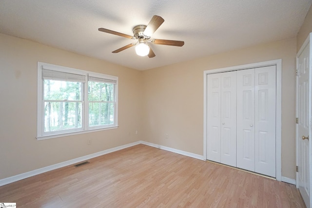 unfurnished bedroom featuring a textured ceiling, ceiling fan, a closet, and light hardwood / wood-style floors