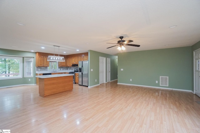 kitchen with a kitchen island, light hardwood / wood-style flooring, hanging light fixtures, stainless steel appliances, and ceiling fan