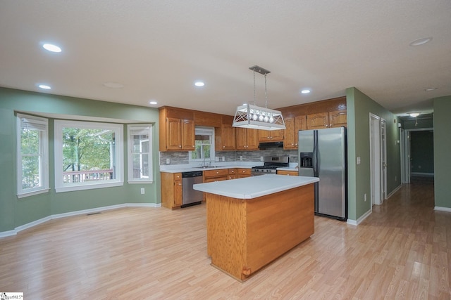 kitchen with hanging light fixtures, a center island, appliances with stainless steel finishes, light hardwood / wood-style floors, and sink