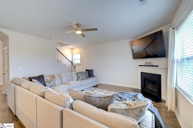 living area featuring ceiling fan, a fireplace, wood finished floors, visible vents, and stairway