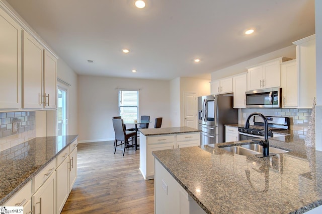 kitchen with appliances with stainless steel finishes, baseboards, backsplash, and a kitchen island