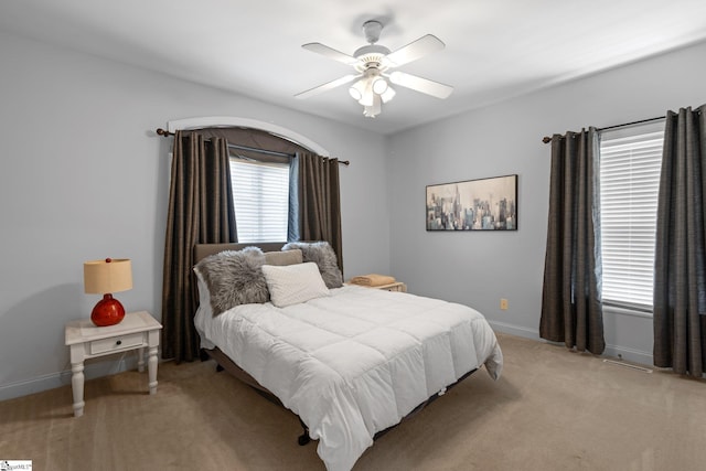 bedroom with baseboards, a ceiling fan, and light carpet