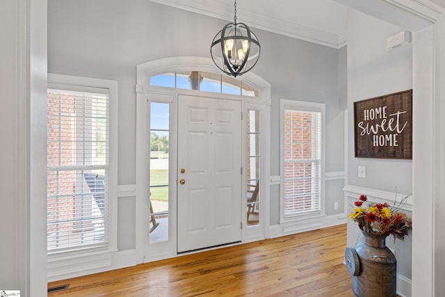 entrance foyer featuring ornamental molding, an inviting chandelier, and light hardwood / wood-style floors