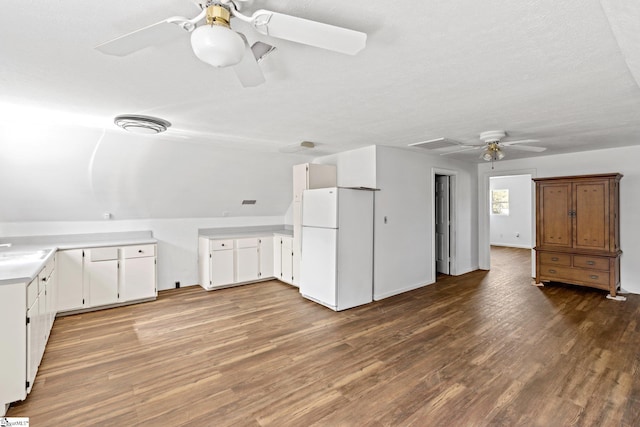 interior space with light wood-type flooring, white refrigerator, white cabinetry, ceiling fan, and a textured ceiling