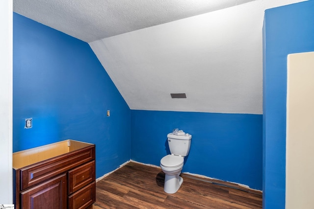 bathroom featuring a textured ceiling, baseboards, wood finished floors, toilet, and vaulted ceiling